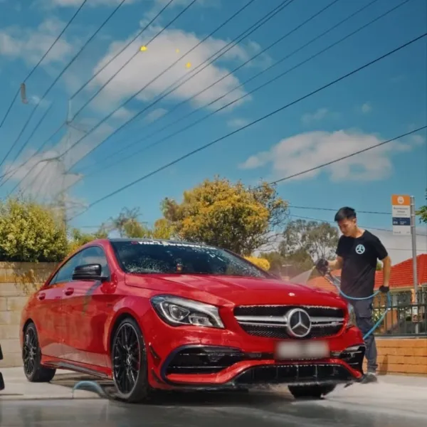 Detailer washing a red Mercedes on location